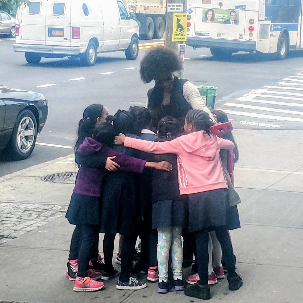 Children and adult in a group huddle on a Bronx city street
